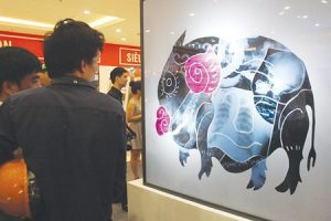 Visitors enjoy an artwork being on display at the exhibition at the Vincom Royal City shopping mall.